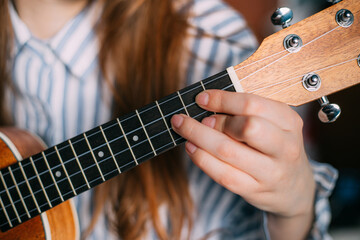 vulture ukulele on a gray background. girl puts a chord