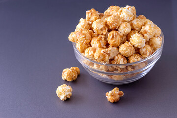 Sweet caramel popcorn in glass bowl. Close up. Light background.