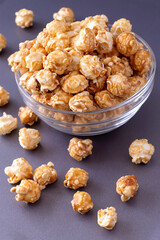 Sweet caramel popcorn in glass bowl. Close up. Light background.