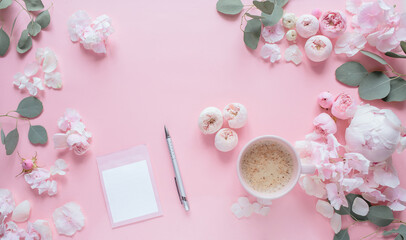 Flowers composition. Empty card, cup of cofee, pen, scissors, and pink flowers on pastel pink background. Flat lay, top view, vertical image.