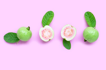 Top view of fresh ripe guava and slices with leaves on pink background.