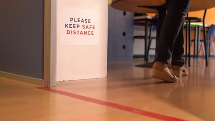 Woman arrives and waits behind a red line to enter a classroom. Social distancing measures for the reopening and adaptation of schools and academies to the new normal.