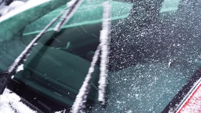 Automobile wipers sweep snow in winter at slow speed. Car windshield in winter, car wipers clean glass
