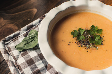 Pumpkin and carrot cream soup on the dark wooden table. Healthy food.