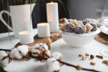 candy in a white plate, nuts, handles on white table 