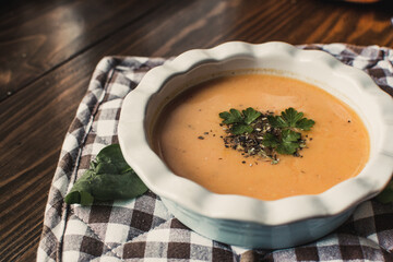 Pumpkin and carrot cream soup on the dark wooden table. Healthy food.