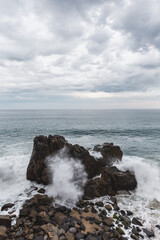 cloudy sunset with waves crashing on rocks