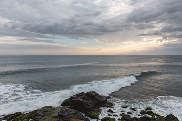 wave washing ashore on a rocky beach at sunset