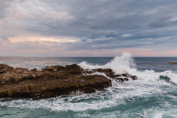 waves crashing on rocks at sunset