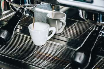 cups getting filled up by a coffee machine with coffee
