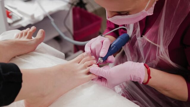 Pedicure master sawing toenails of a woman.
