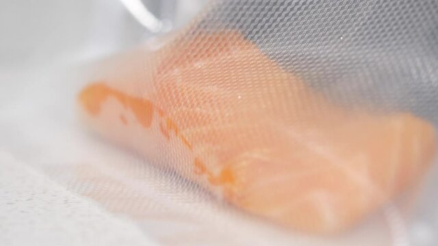 Fresh fish fillet vacuumed packed into plastic bag. Raw salmon steak getting prepared to be stored. 
