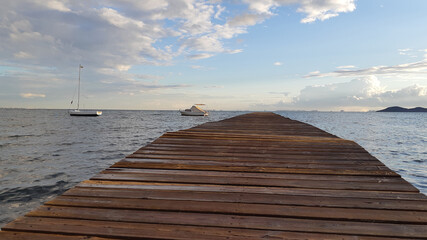 wooden pier goes out to sea, boats at sea and the silhouette of the city on the horizon