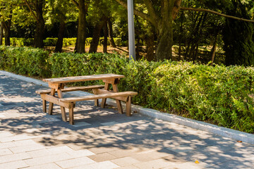 Wooden picnic table in park next to hedges