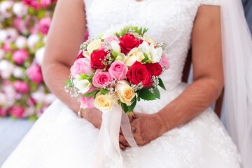 Obraz na płótnie Canvas Indian couple's hands holding a beautiful wedding bouquet red and pink roses