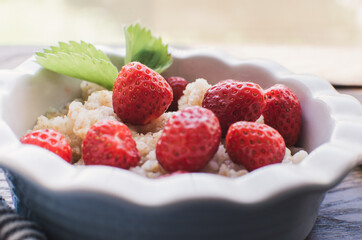 Breakfast. Tasty oatmeal with berries. Healthy breakfast ingredients. Oat granola in bowl with strawberry and mint. Granola for breakfast with berries.