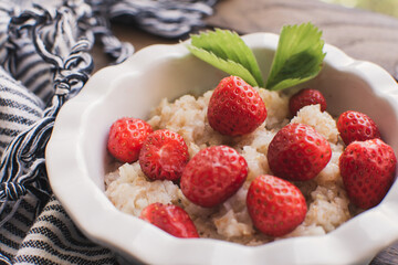 Breakfast. Tasty oatmeal with berries. Healthy breakfast ingredients. Oat granola in bowl with strawberry and mint. Granola for breakfast with berries.