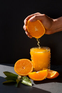 Mans hand sqeezing orange juice into the glass in the bright sunlite