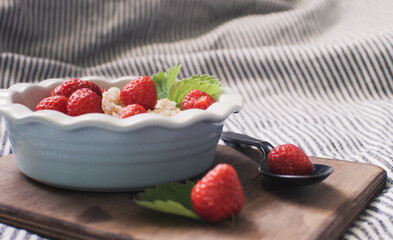 Breakfast. Tasty oatmeal with berries. Healthy breakfast ingredients. Oat granola in bowl with strawberry and mint. Granola for breakfast with berries.