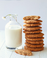 Oatmeal cookies and milk in bottle, healthy snack. Light background. Daisy flower