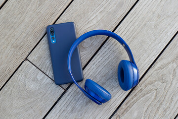 Blue headphones and smartphone on wooden background