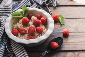 Breakfast. Tasty oatmeal with berries. Healthy breakfast ingredients. Oat granola in bowl with strawberry and mint. Granola for breakfast with berries.