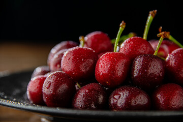 Ripe red cherries in black plate.
