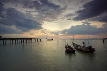 Dramatic sunset scenery at seascape with long jetty background.