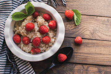 Breakfast. Tasty oatmeal with berries. Healthy breakfast ingredients. Oat granola in bowl with strawberry and mint. Granola for breakfast with berries.