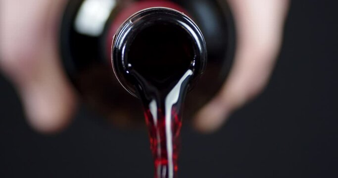 Male hand holding a bottle with spilling wine.