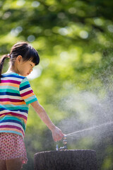 真夏の公園で水遊びをしている可愛い子供