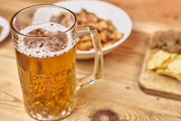 A glass of beer and different snacks on the table. Celebrating international beer day or Octoberfest. Drinking beer after a hard working day or week