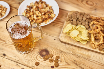 A glass of beer and different snacks on the table. Celebrating international beer day or Octoberfest. Drinking beer after a hard working day or week