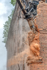 Fototapeta na wymiar Excavator destroyer breaks a brick wall.