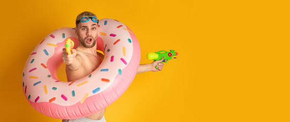 Guy in inflatable ring shoots water guns