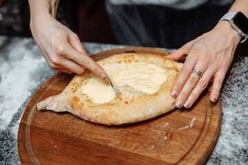 Chef cooking khachapuri with cheese and egg. Georgian national cuisine