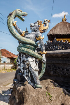 Statue of Hanuman, Hindu god and divine monkey (vanara) companion of the god Rama, fighting naga (snake). Bali, Indonesia. Vertical image.