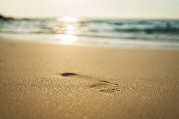 footprints in the yellow sand with waves