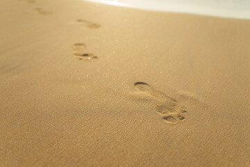 Fototapeta na wymiar footprints in the yellow sand with waves