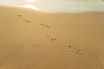 Fototapeta na wymiar footprints in the yellow sand with waves