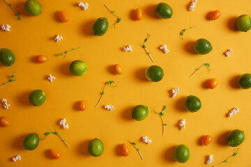 Top view of fresh green limes, cumquat, peas sprouts and popcorn on yellow background. Organic nutrition and healthy eating concept. Source of vitamins. Closeup. Composition of nutrient products