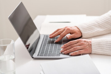 Home office concept. Mature woman hand typing on laptop