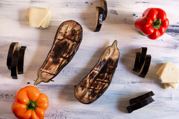aubergines with cheese and chili peppers in a pattern on blue artistic wooden background