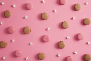 Dessert, food, sugar, calories. Tasty chocolate and strawberry macaroons with marshmallow on rosy background. Traditional sweet tasty french cookies. Creative pattern. Colorful confectionery products