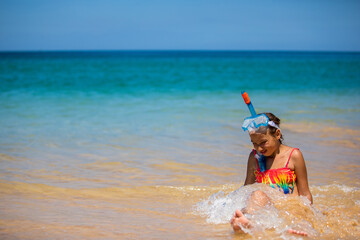 Happy child girl in a mask on the beach in summer