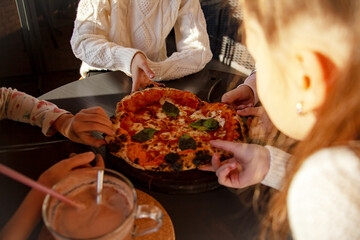 Top view image of children hands grab slice pizza. Group of kids eating italian food in in cafe. Hungry children holding appetite piece of tasty pizza. People celebrating birthday in pizzeria.