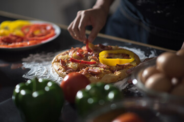 close-up of human hands in the apron knead the dough on a black wooden table, sprinkle with flour.Making dough by hands at bakery.
