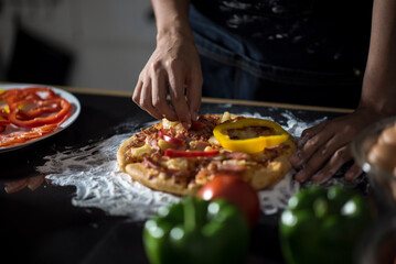 close-up of human hands in the apron knead the dough on a black wooden table, sprinkle with flour.Making dough by hands at bakery.