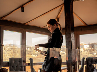 Female posing in cafe  on the roof of the city and using a laptop.  Fashion woman dressed style black  golf and shorts. Freelancer relexing on the rooftop and holding computer.