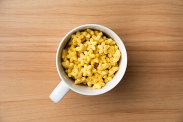 Star shaped honey coated cereal in a white glass and wooden background.